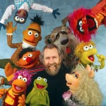 Jim_Henson_surrounded_by_Muppets_Fraggles_Sesame Jim_Henson_surrounded_by_Muppets_Fraggles_Sesame
